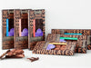 six gourmet chocolate bars artfully arranged with a few broken pieces stacked in front.
