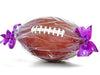 Life size molded chocolate football has pigskin texture and white chocolate laces stitching details. It is wrapped in clear cellophane and tied at each end with a tribbon.