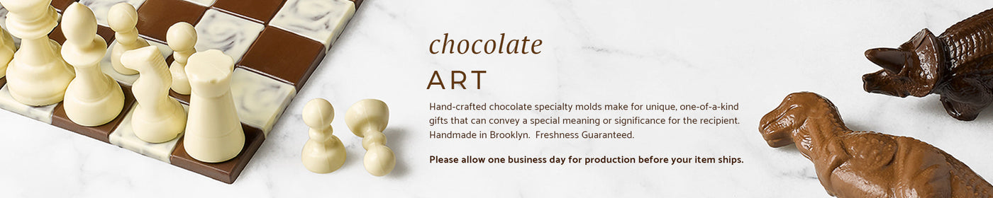 A chocolate chess set and two chocolate dinosaurs on a marble background.