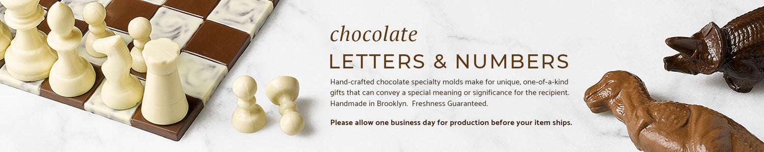 A chocolate chess set and two chocolate dinosaurs on a marble background.