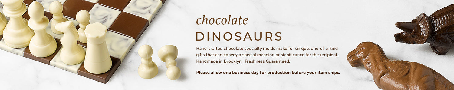 A chocolate chess set and two chocolate dinosaurs on a marble background.