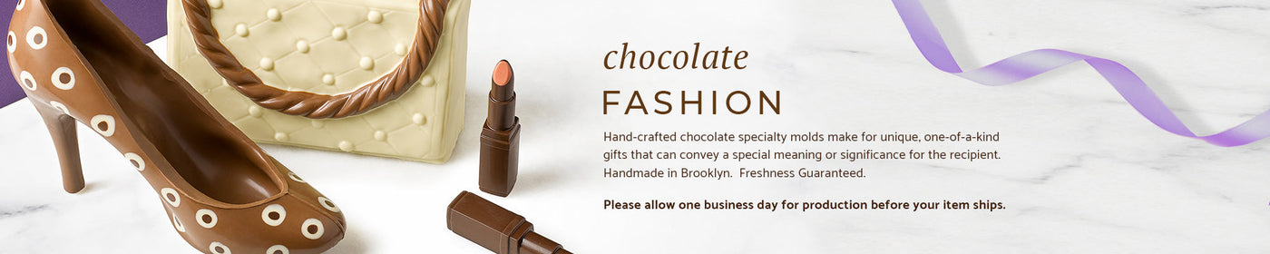 a milk chocolate high heel, a white chocolate handbag, and two chocolate lipsticks on a marble background and a strand of purple ribbon.