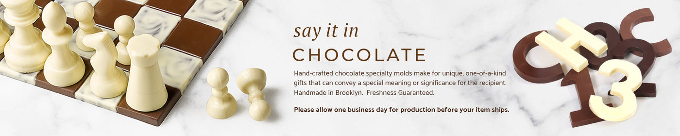 A chocolate chess set and two chocolate dinosaurs on a marble background.