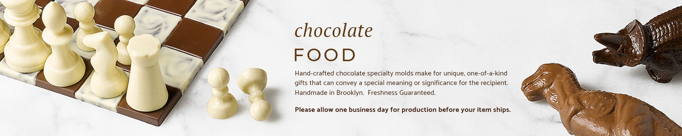 A chocolate chess set and two chocolate dinosaurs on a marble background.