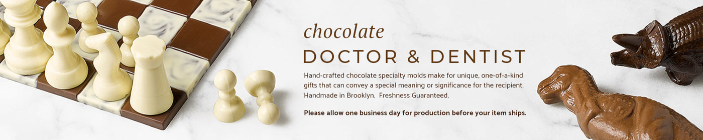A chocolate chess set and two chocolate dinosaurs on a marble background.