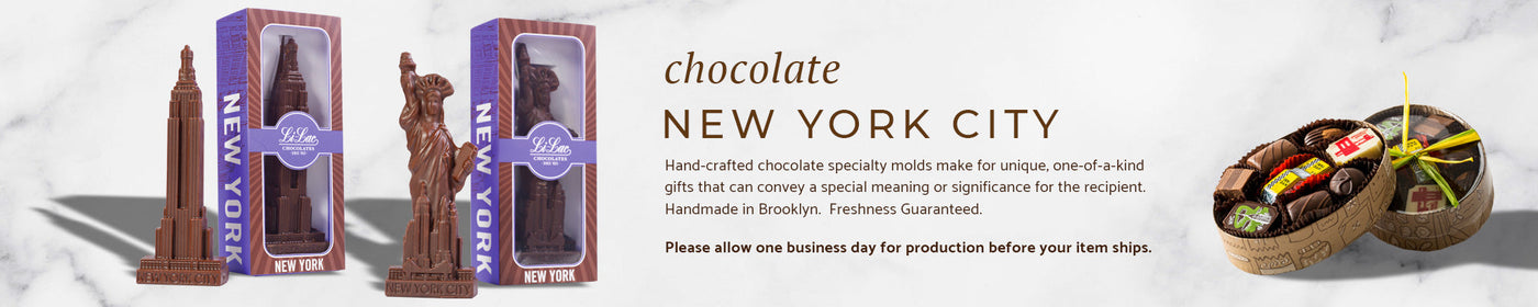 a chocolate empire state building and statue of liberty on a marble background, and another box of chocolate with an NYC taxi in the center of the box.