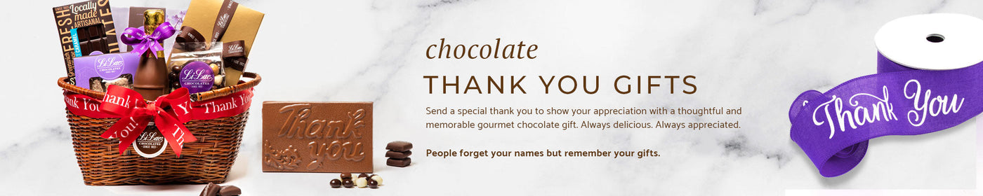 A basket of chocolate with a thank you chocolate bar next to it and a roll of purple ribbon that says Thank You.