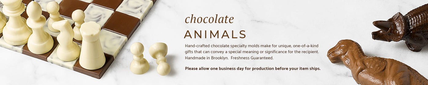 A chocolate chess set and two chocolate dinosaurs on a marble background.