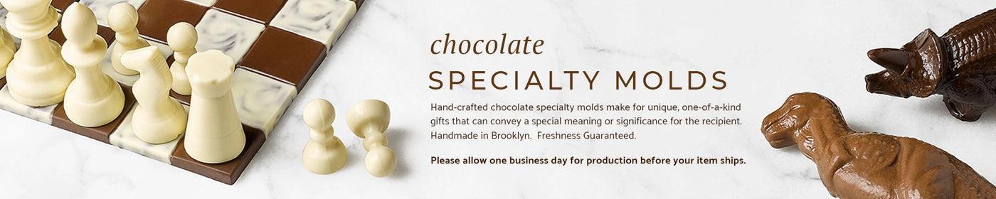 A chocolate chess set and two chocolate dinosaurs on a marble background.