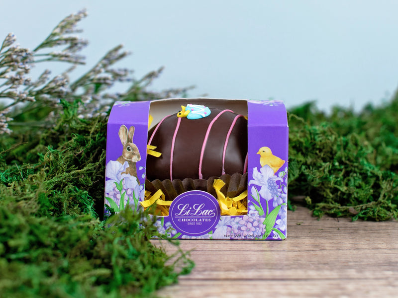 A colorful lilac box decorated with a bunny and chick with one large decorated Easter Egg inside.