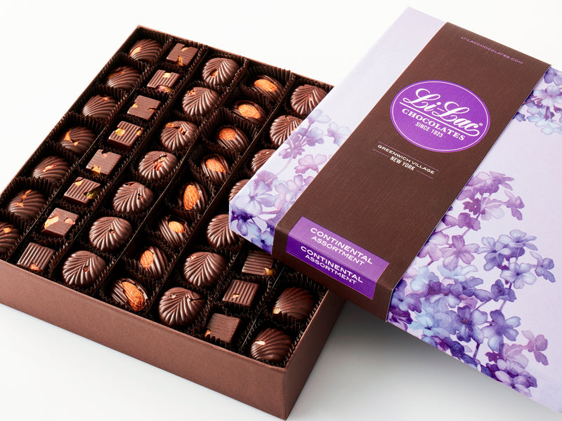 A rectangular box of chocolate with a brown base and a purple lid with watercolor lilac motifs. 