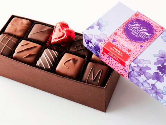 An open box showing the chocolate with a Valentine-motif box top partially covering the chocolates