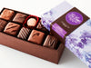 A large rectangular box of chocolate with a brown base and a purple lid with watercolor lilac motifs. 