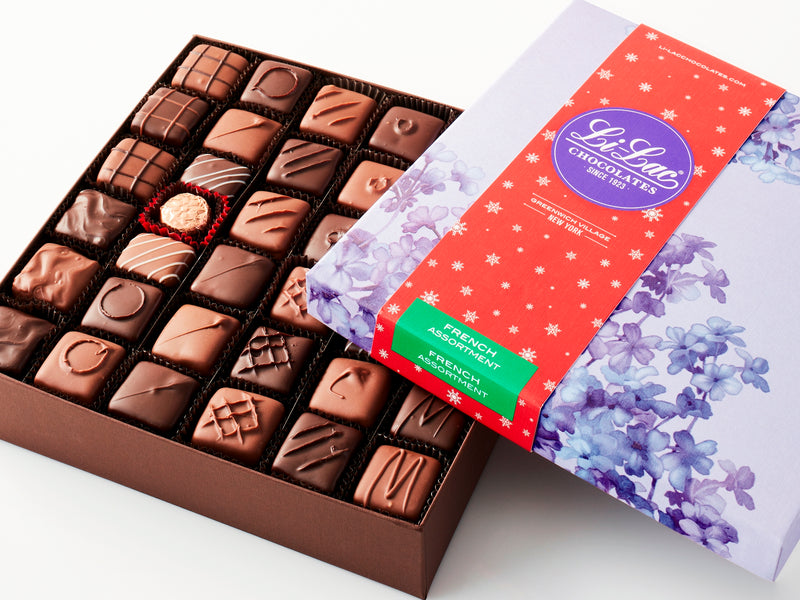 An open box showing the chocolate pieces with a red starry holiday sleeve on the box top