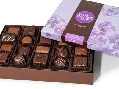 A large rectangular box of chocolate with a brown base and a purple lid with watercolor lilac motifs. 