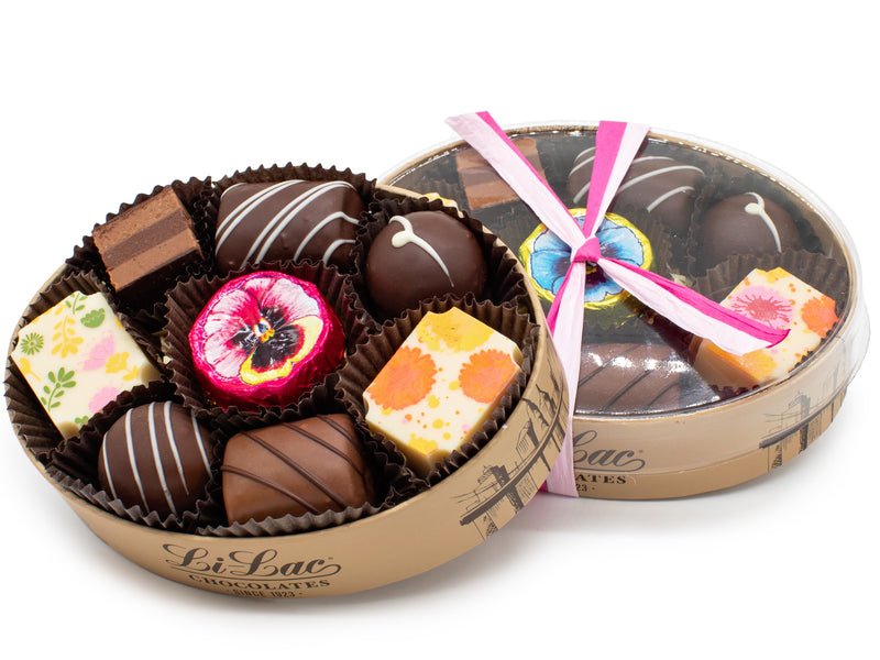 A oval box with a clear lid filled with 9 colorful chocolates. of chocolates.