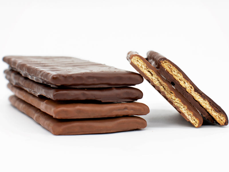 A stack of four chocolate covered graham crackers with two additional pieces showing the inside of the cracker. 