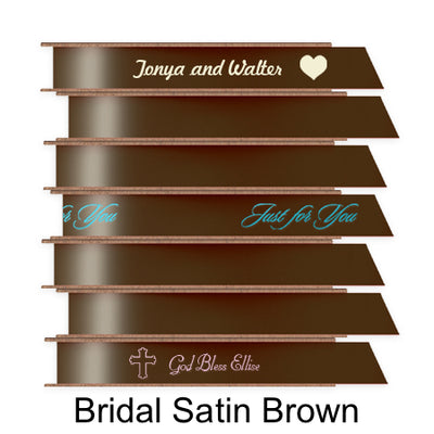 A stack of seven spools of shiny brown satin ribbon with custom messages printed on them in different colors. 