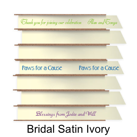 A stack of seven spools of shiny ivory satin ribbon with custom messages printed on them in different colors. 