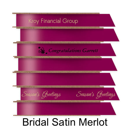 A stack of seven spools of shiny merlot satin ribbon with custom messages printed on them in different colors. 