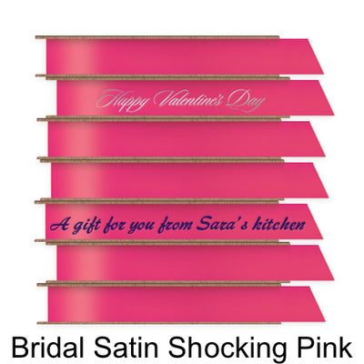 A stack of seven spools of shiny bright pink satin ribbon with custom messages printed on them in different colors. 