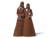 Three-dimensional molded chocolate Brides stand together with their arms entwined.