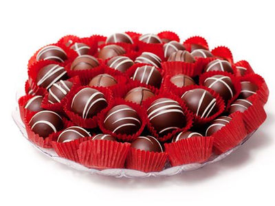 Two layers of beautiful assorted truffles sit, stacked in two layers on a serving tray.