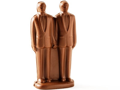 Two molded chocolate Grooms stand side by side in smart suits holding hands.