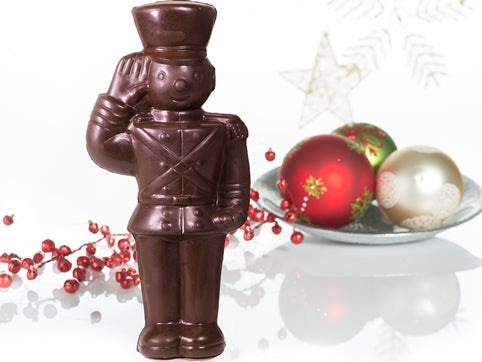 A large molded chocolate toy soldier stands at attention, saluting.