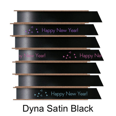 A stack of seven spools of shiny black satin ribbon with custom messages printed on them in different colors. 