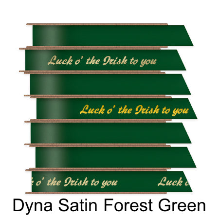 A stack of seven spools of shiny forest green satin ribbon with custom messages printed on them in different colors. 