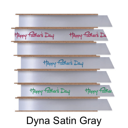 A stack of seven spools of shiny soft gray satin ribbon with custom messages printed on them in different colors. 