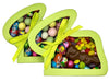 Green box shaped like a bunny with a clear lid holds Easter themed candy and chocolates.