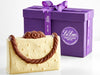 White Chocolate Handbag shown with its purple box and Li-Lac ribbon. The handbag has a milk chocolate handle and floral clasp.