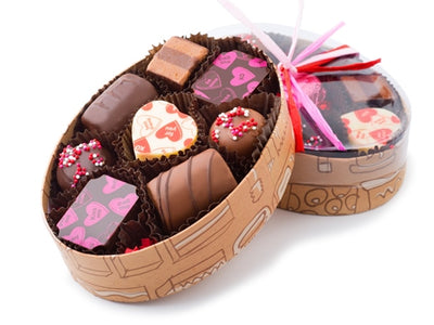 A small oval box holds eight piece of assorted chocolates with Valentine decorations.