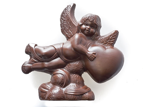 A molded chocolate Angel flying atop some clouds holding a heart.with a Heart