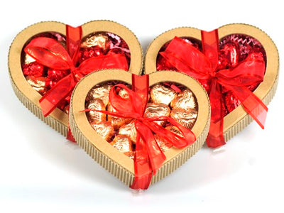 Kraft paper chocolate hearts are filled with foil wrapped chocolate hearts and the box is tied with a festive ribbon. 