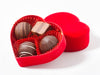 Four assorted chocolate truffles sit inside a little heart shaped box.