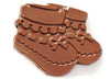 Milk chocolate molded into the shape of a pair of two-dimensional baby booties.