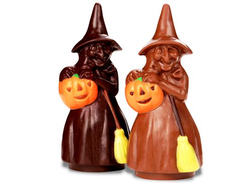 A big molded chocolate witch carries a jack-o-lantern friend and a broom stick. She wears a tall pointed witch&