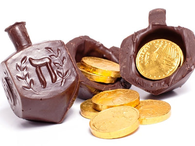 A chocolate molded dreidel is filled with a couple of pieces of foil wrapped Gelt.
