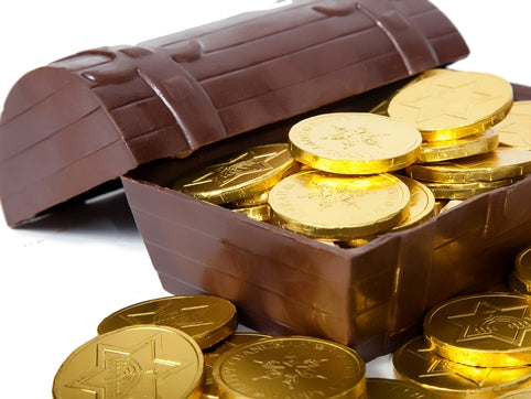 A treasure chest made of molded chocolate sits with the removeable lid half off. Inside the chest is filled with chocolate coins wrapped in gold foil.