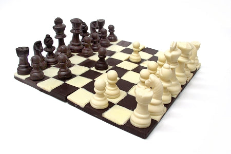 A chocolate molded chess set. The base is made up of four flat pieces set together, with a dark and white chocolate checkerboard pattern. The white chocolate and dark chocolate sides are individually molded life-size chess pieces.
