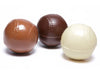 Three chocolate baseballs sit together; one milk chocolate, one white chocolate and one dark chocolate.