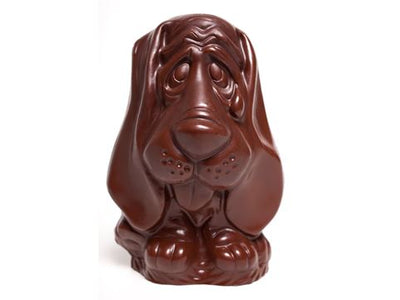 A sitting dark chocolate molded basset hound. He has cute big ears and a little tongue sticking out.