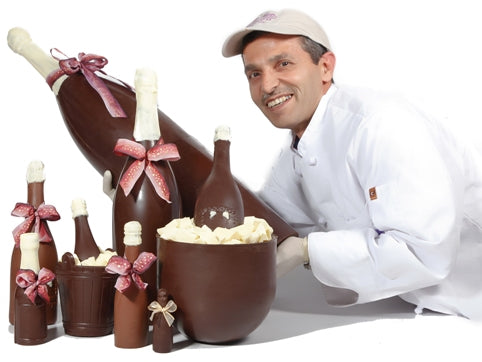 The Master Chocolatier holds a giant molded chocolate champagne bottle.