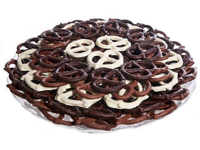 Thin pretzels, enrobed in white, milk and dark chocolate, are artfully stacked together in layers on a round platter.