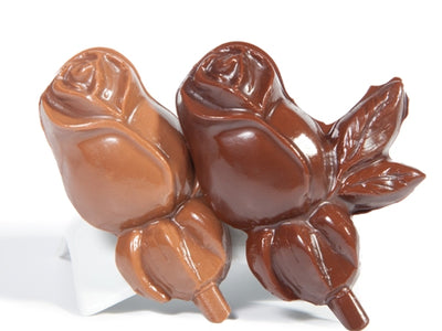 Molded chocolate rosebuds with leaves are on a lolly stick.