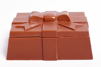 A three-dimensional chocolate molded square box with ribbon detailing. The lid can be removed.