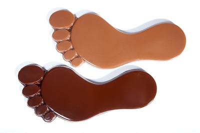 Chocolate molded into the shape of two-dimensional foot Prints. You can see the sole of the foot as well as each toeprint.